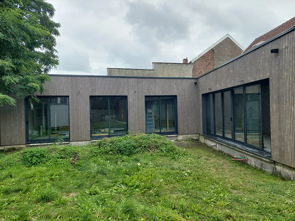 extérieur d'une maison en bois avec baies vitrées et contour en plastique noir